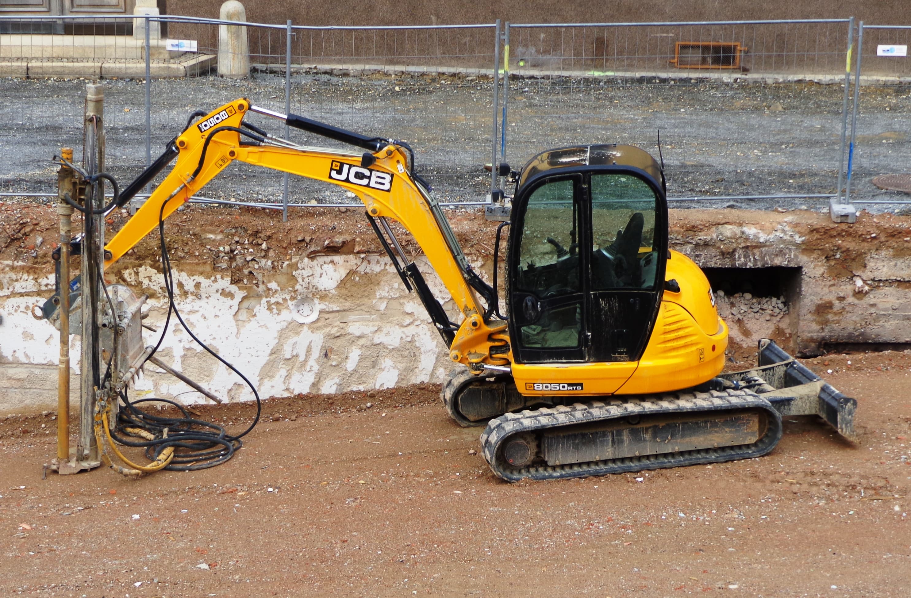 JCB mini excavator parked beside a hydraulic breaker attachment on a foundation site